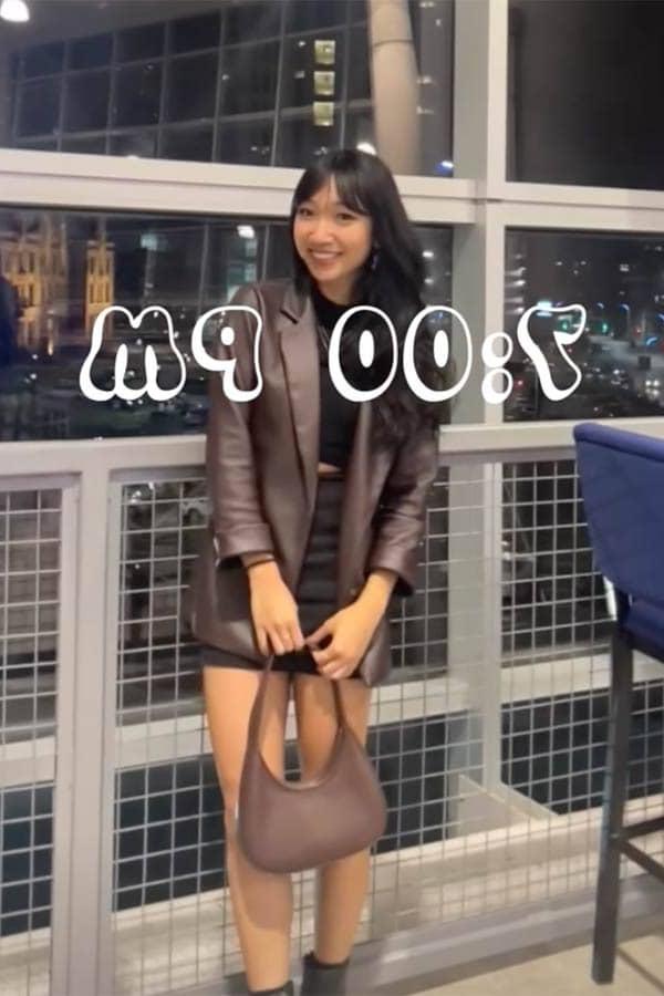 Yennhi Phan, a female student stands in Busch Student Center. She is nicely dressed and carrying a large brown purse. A large time stamp over the image in a fun font.